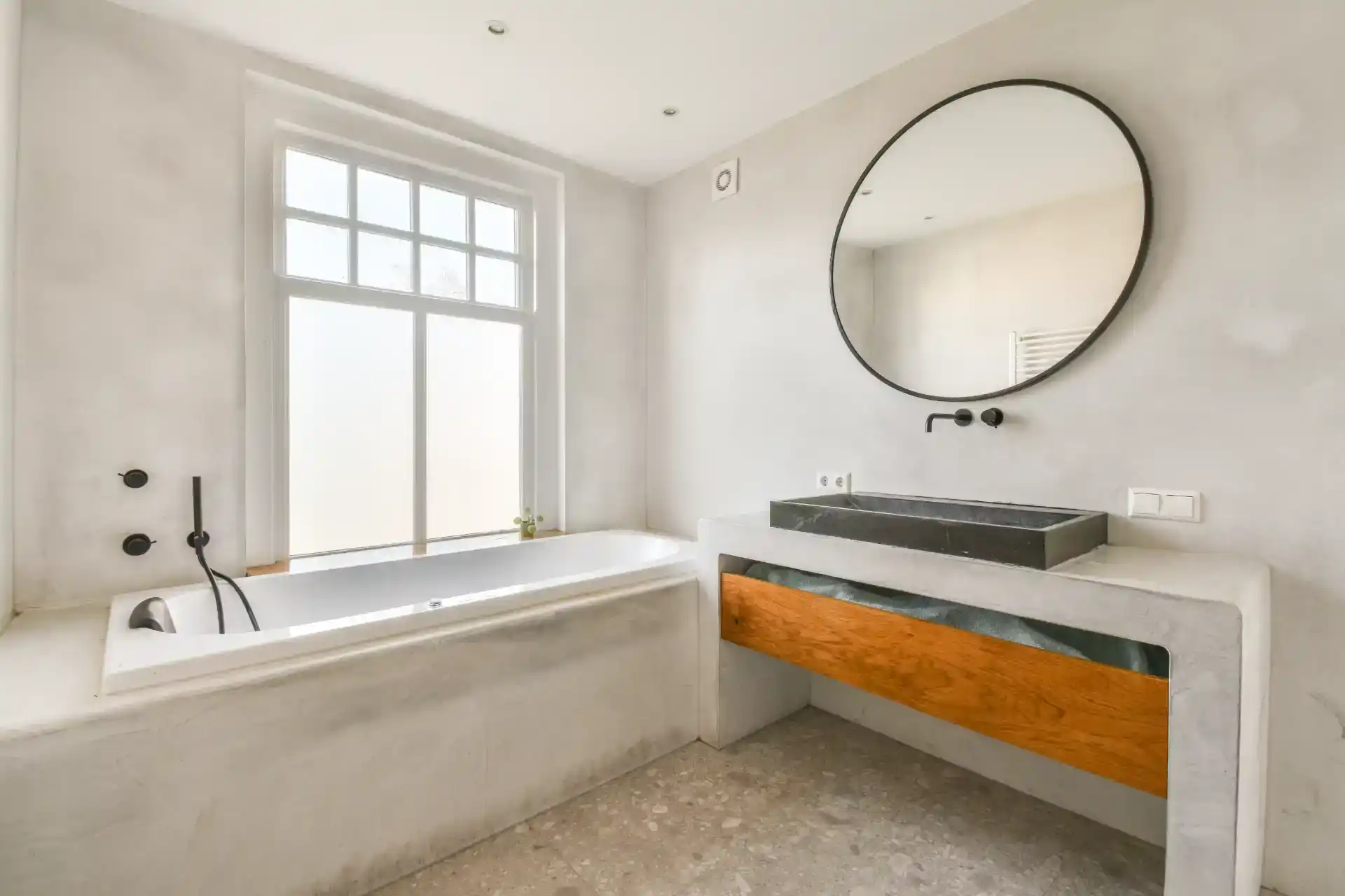 Moderne badeværelse med minimalistisk design, stor vindue og fritstående badekar.